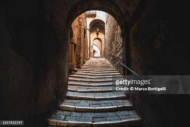 uphill alley with stairs in an old turf village, italy - village foto e immagini stock