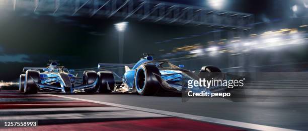 två racerbilar rör sig i hög hastighet under night race - racerbil bildbanksfoton och bilder