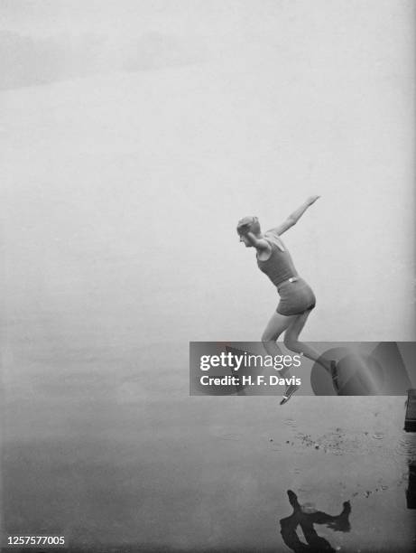 Woman wearing one-piece swimsuit and pool cap dives into the Serpentine Lake, London, UK, 29th October 1932.