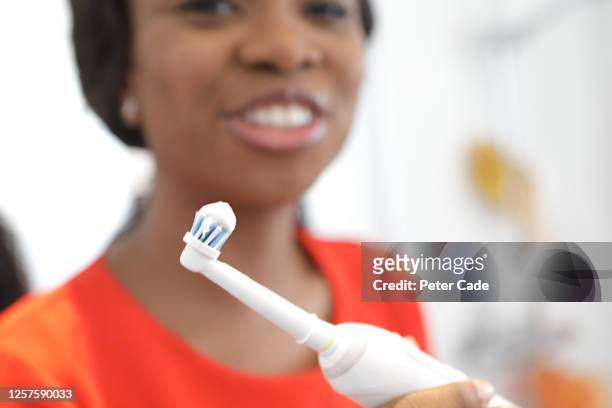 woman brushing teeth with electric toothbrush - bristle stock pictures, royalty-free photos & images