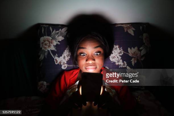 woman in bed on phone at night - shock stock photos et images de collection