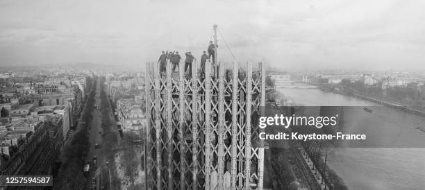 Ouvriers perchés au sommet de l'une des tours en bois de la porte de la place de l'Alma, lors du chantier de l'Exposition universelle de 1937 de...