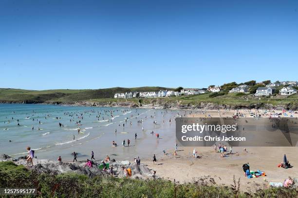 Beachgoers enjoy Polzeath beach on July 21, 2020 in Polzeath, United Kingdom. Many UK residents have decided to go on 'staycations' to Devon and...