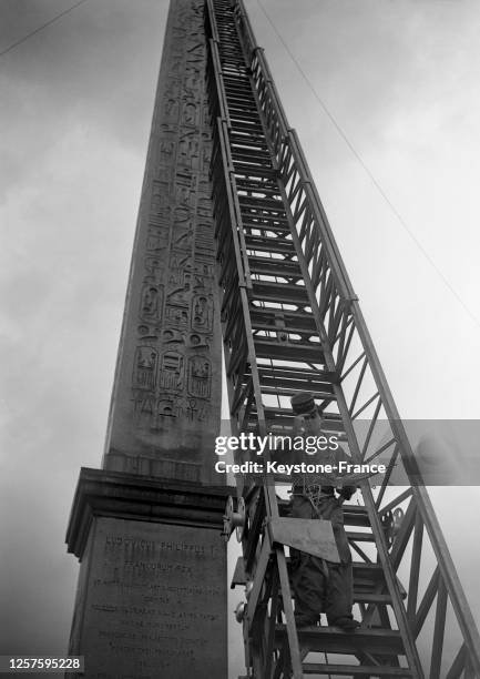 Escalade de l'obélisque de la place de la Concorde avec la grande échelle des pompiers par Mario Fabre, jeune camelot se faisant passer pour un...