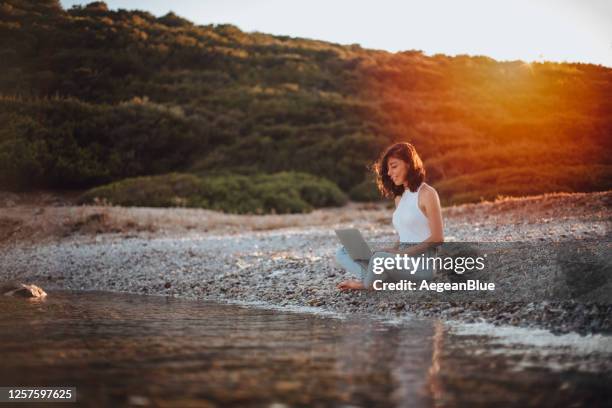 freelancer frau arbeitet am laptop am strand - using mobile stock-fotos und bilder