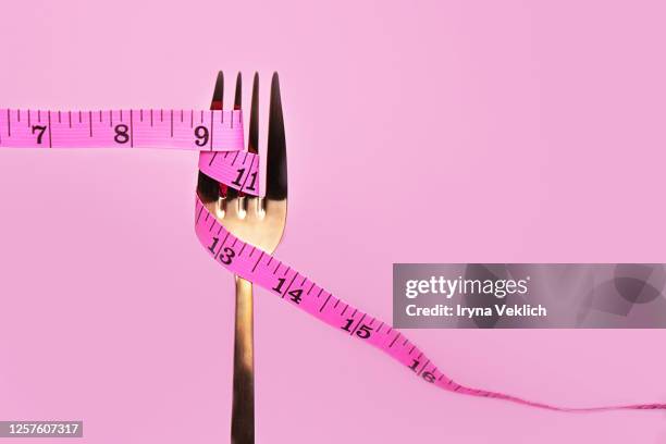 pink measuring tape and fork on pink background. - fat loss stock-fotos und bilder