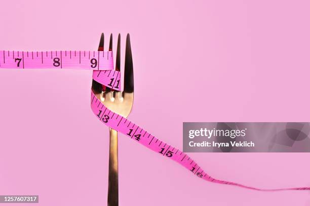 pink measuring tape and fork on pink background. - fat imagens e fotografias de stock