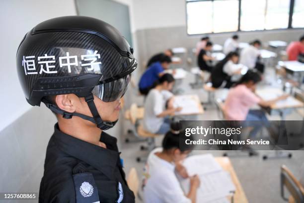 Security guard wears a smart helmet equipped with a thermo-scan sensor to check the body temperature during an exam at a middle school on July 22,...