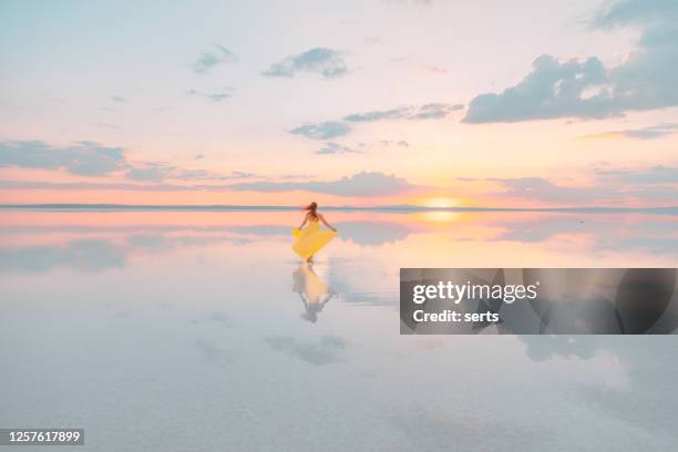 junge frau genießt sonnenuntergang am salt lake - women in see through dresses stock-fotos und bilder