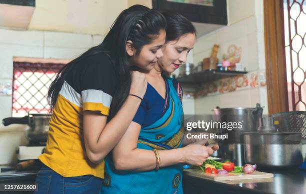 indische mutter lehrt ihre tochter, wie man gemüse hackt und tochter hilft mutter in der küche. - indian mother daughter stock-fotos und bilder