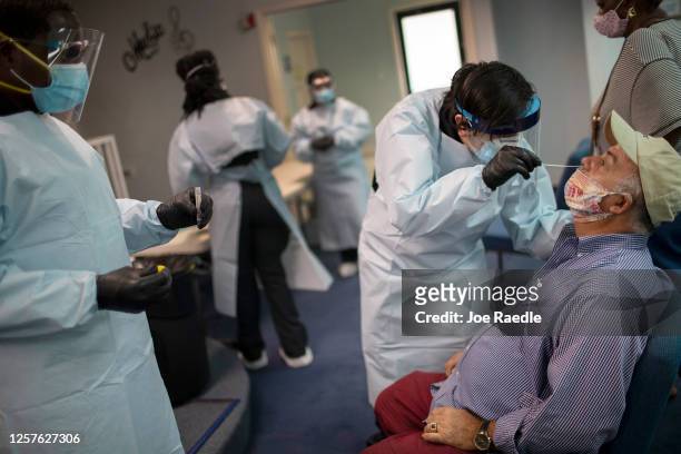 Health care worker use a nasal swab to test Marcelino Soto for COVID-19 at a pop up testing site at the Koinonia Worship Center and Village on July...