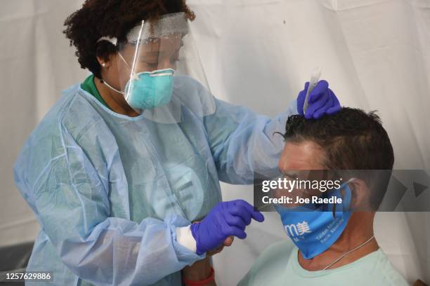 Dr. Jacqueline Delmont, Chief Medical Officer of SOMOS Community Care, uses a nasal swab to test Eddie Mena for COVID-19 in a medical tent at a...