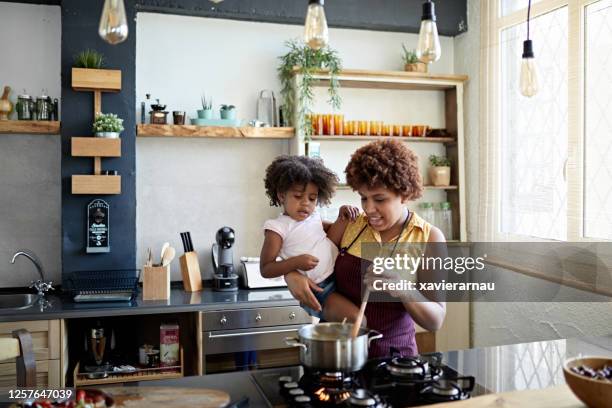 mutter hält 3 jahre alte tochter und kochnudeln - black mother and child cooking stock-fotos und bilder