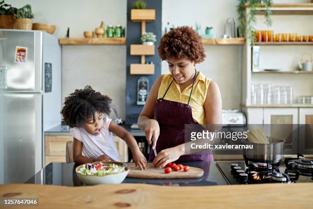 afro-caribische moeder en jonge dochter koken samen - stay at home mother stockfoto's en -beelden