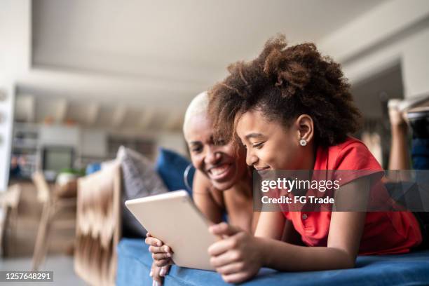 mère et famille regardant le film dans une tablette numérique à la maison - famille jeux société photos et images de collection