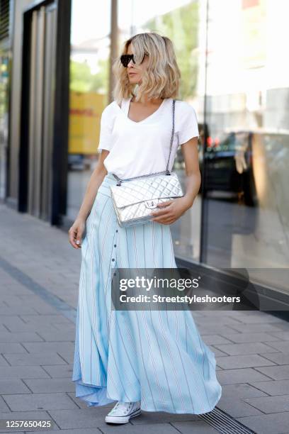 Influencer Gitta Banko wearing sunglasses by Bottega Veneta, a long maxi skirt in different shades of blue, a silver colored bag by Chanel, a white...