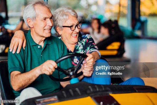 verticale d’un couple aîné ayant l’amusement au parc d’attractions - parc dattractions photos et images de collection