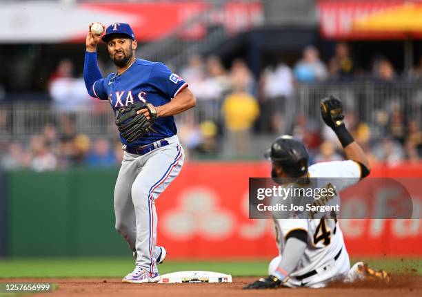 Marcus Semien of the Texas Rangers turns a double play over Carlos Santana of the Pittsburgh Pirates in the fourth inning at PNC Park on May 23, 2023...