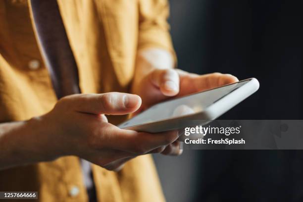 hombre anónimo que lleva una camisa yelow usando la tecnología moderna, un primer plano - social media fotografías e imágenes de stock