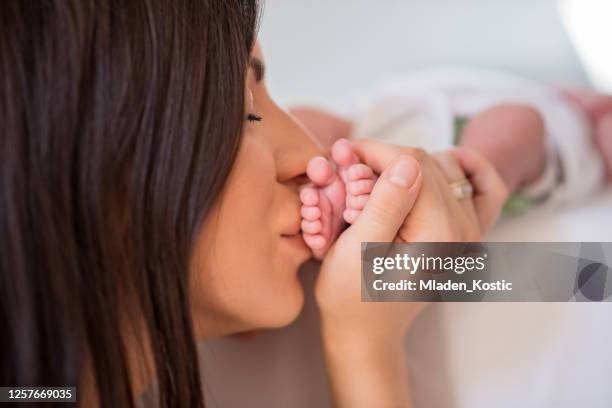 moeder die de voeten van de kleine baby, close-up houdt en kust - feet kiss stockfoto's en -beelden