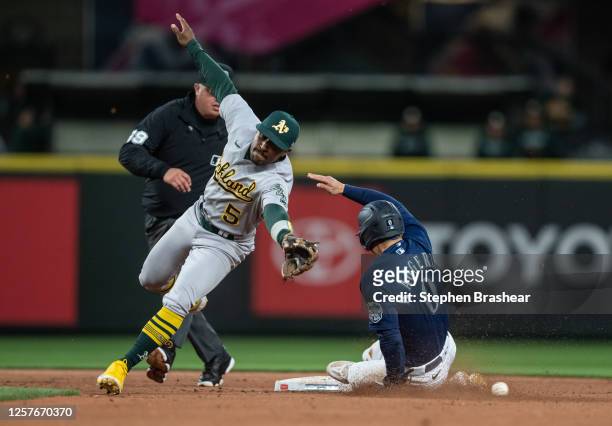 Sam Haggerty of the Seattle Mariners steals second base as second baseman Tony Kemp of the Oakland Athletics is unable to field a throw by catcher...