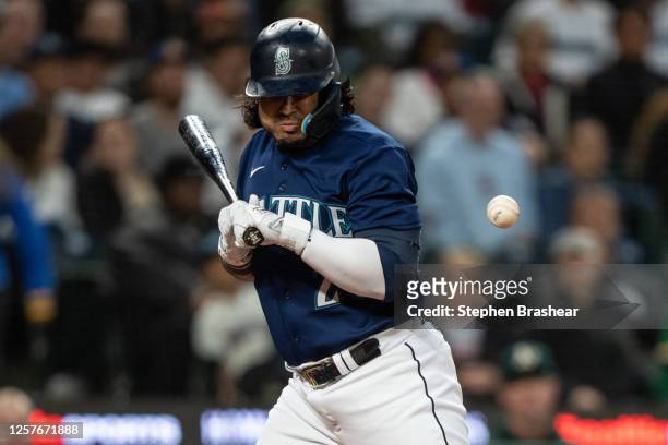 Eugenio Suarez of the Seattle Mariners is hit by a pitch thrown by relief pitcher Trevor May of the Oakland Athletics during the eighth inning of a...