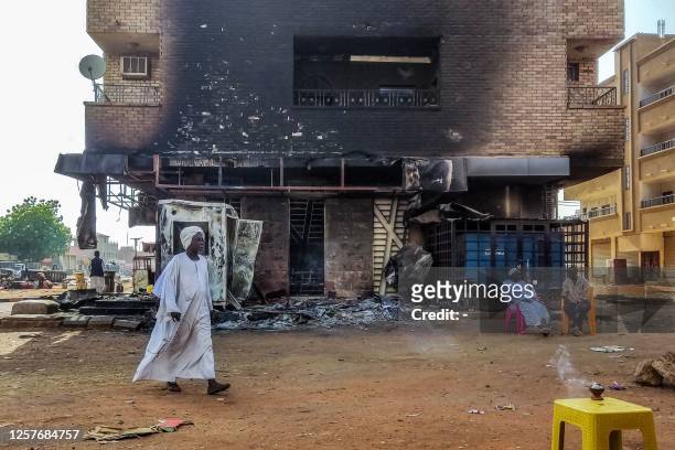 Man walks past a burnt out bank branch in southern Khartoum on May 24, 2023. Sporadic artillery fire still echoed in Sudan's capital on May 24 but...