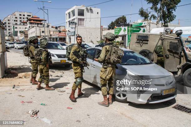 Israeli soldiers guard an Israeli settler's car after it was pelted with stones in a Hawara town, south of Nablus, in the occupied West Bank. Two...