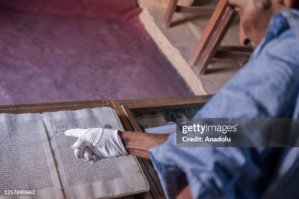 Abdullah Habott, the book preserver, wears gloves as he handles by ancient handwriting manuscripts in Chinguetti, Mauritania on May 10, 2023. The...