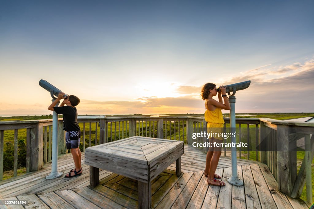 Siblings looking through binoculars
