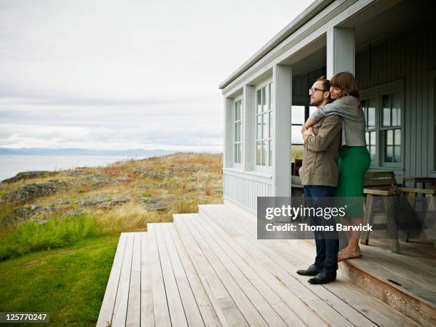 young couple embracing on porch of home - summer home stock pictures, royalty-free photos & images