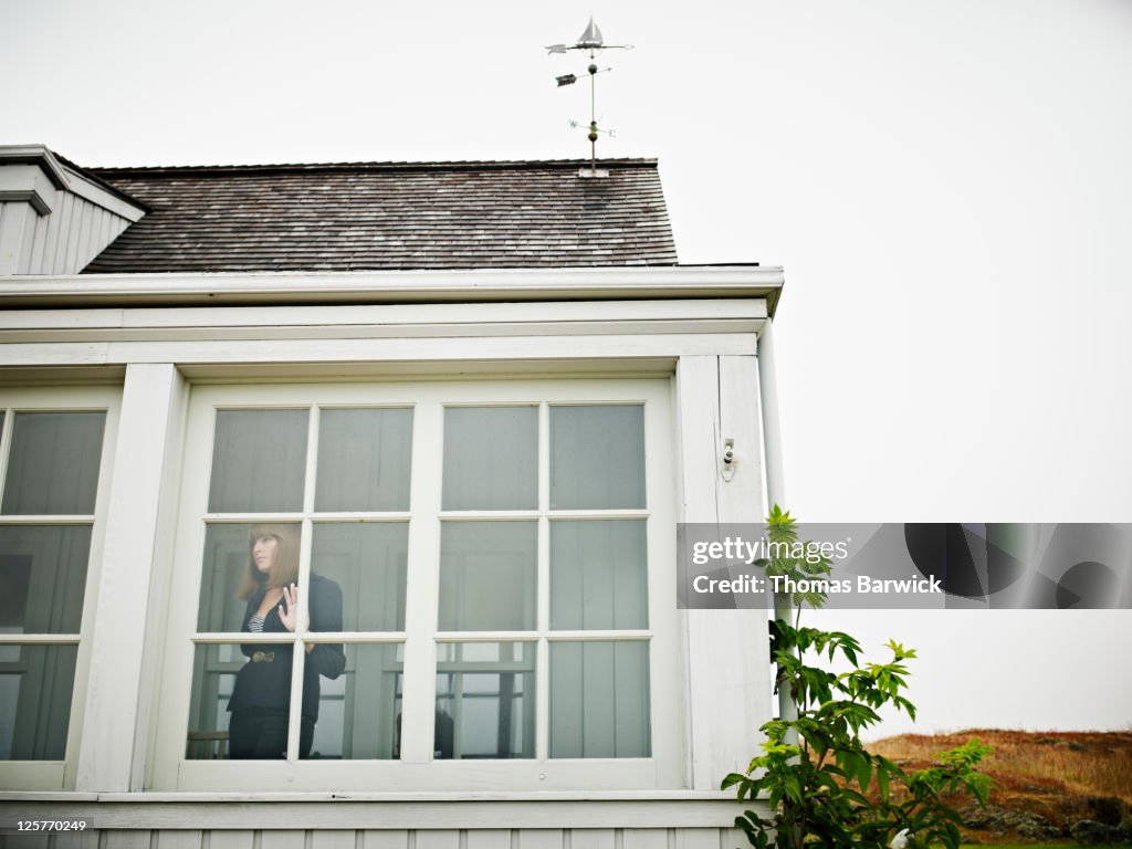 Woman standing behind window on front porch