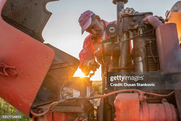 landwirt, der auf landwirtschaftlichen geräten in einem landwirtschaftlichen betrieb arbeitet - landwirtschaftliche maschine stock-fotos und bilder