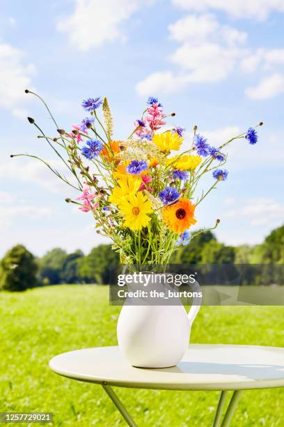 colorful bouquet of wild flowers in a vase on table in garden - bouquet stock-fotos und bilder