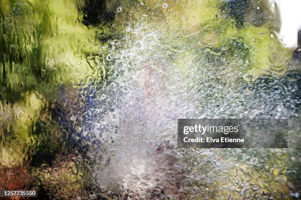 water sprayed onto a window from a garden hose held by a teenager - hose stock pictures, royalty-free photos & images