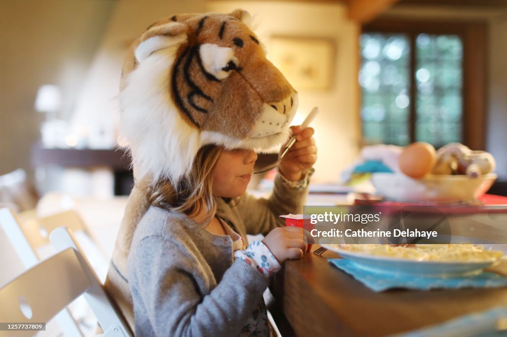 A little girl disguised as a tiger eating her yogurt