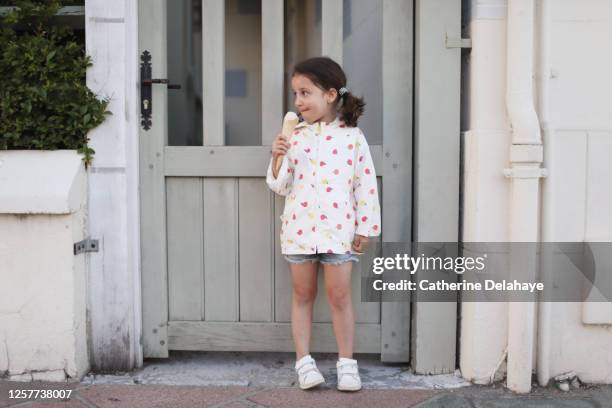 a 5 year old girl eating a icecream in the street - pigtails stock pictures, royalty-free photos & images