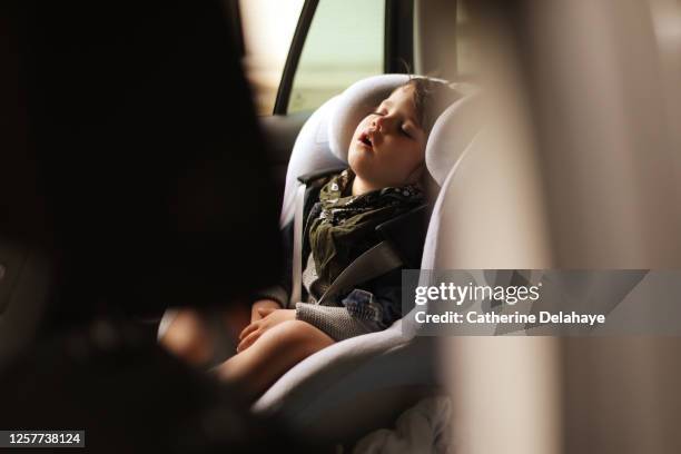 a 3 year old little boy sleeping in a car - child car seat foto e immagini stock