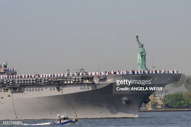 Sailors and Marines stand on the flight deck of the USS Bataan, a Wasp-class amphibious assault ship, as it passes the Statue of Liberty during Fleet...
