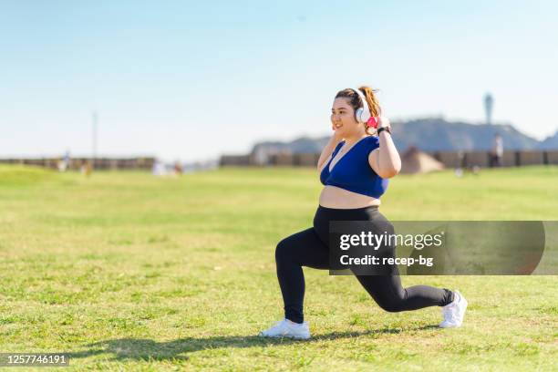 young female athlete doing muscle trainings with dumbbells at public park - fat asian woman stock pictures, royalty-free photos & images