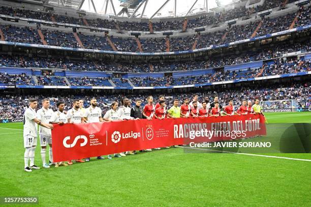 Real Madrid's and Rayo Vallecano's players hold a banner reading 'Racists, out of football' in support to the Real Madrid's Brazilian forward...