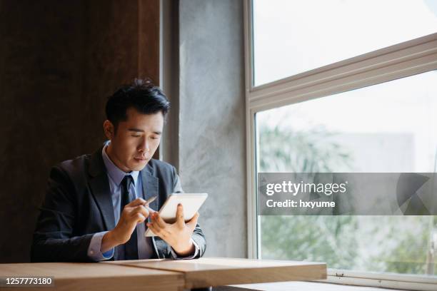 young asian businessman working with digital tablet and stylus pen - pda stock pictures, royalty-free photos & images