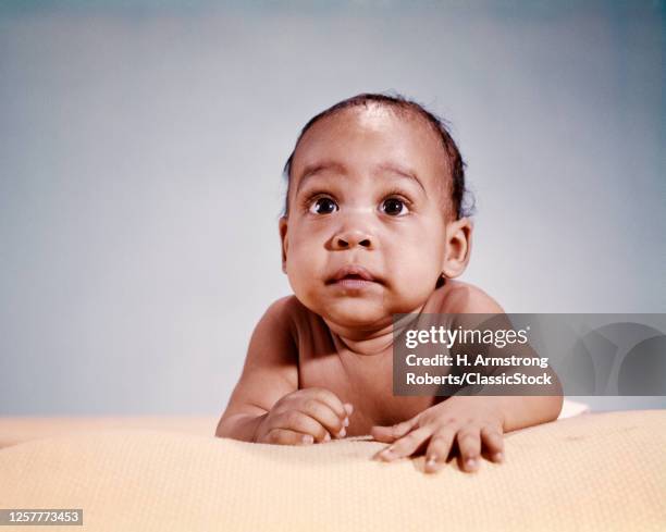 1960s Wide-Eyed Startled Surprised African-American Baby Boy Portrait Eager Facial Expression Crawling On Cotton Summer Blanket