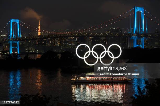 Illuminated Olympic rings are seen in front of the Rainbow Bridge and the Tokyo Tower at night on the day marking one year to go until the Tokyo...