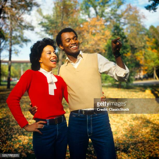 1980s Smiling African-American Couple Smiling Arm In Arm Outdoors In Autumn Wearing Knit Sweaters And Denim Blue Jeans