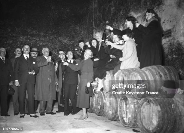 Les voyageurs du 'Train du Vin' dégustent du vin dans une cave de Vouvray, en France le 19 octobre 1936.