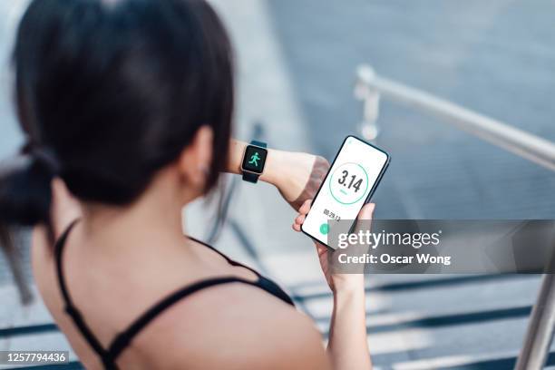 woman checking her smart watch and mobile phone after run - checking sports fotografías e imágenes de stock