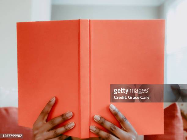 woman reads book on sofa - livre à couverture rigide photos et images de collection