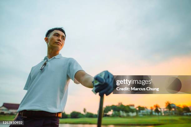 aziatische chinese mannelijke jonge golfer hand die golfclub bij golfcursus met mooie zonsondergang houdt - men's water polo stockfoto's en -beelden