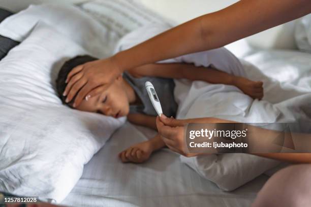 mother checking her sick sons temperature - fever stock pictures, royalty-free photos & images